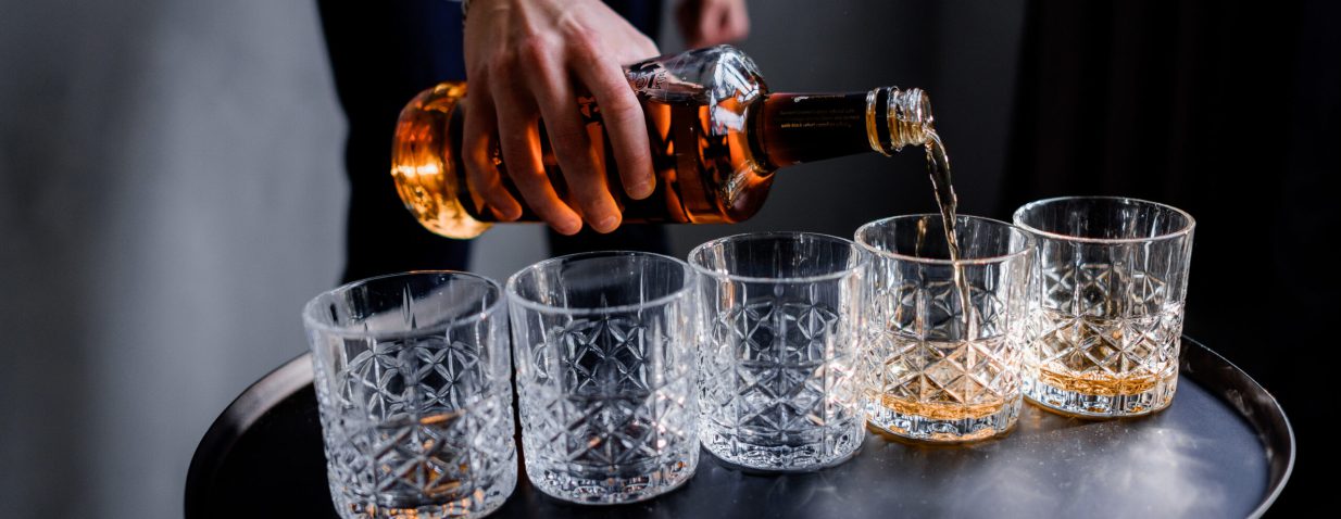 Man is pouring the strong alcohol drink into the glass